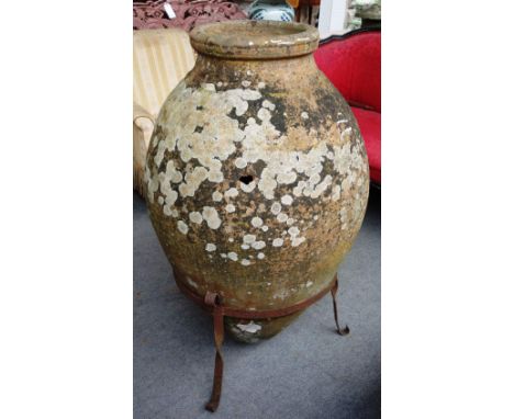 A large terracotta oil jar of typical form, in a wrought iron cradle (a.f),120cm high.
