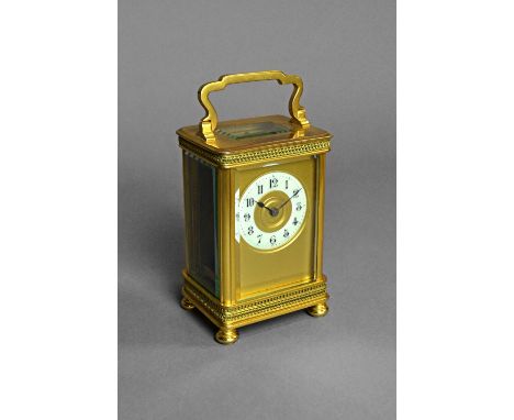 A French brass carriage timepieceCirca 1900The case with a shaped handle, above the gilt dial and off-white enamelled chapter