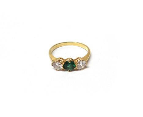 A gold, diamond and green gem set three stone ring, claw set with the circular cut green stone at the centre, between two cir