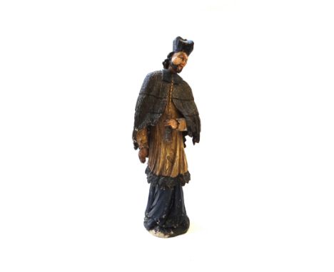A North European polychrome carved wood figure of a cleric, early 19th century, with tasselled cloak and long robe (a.f), 57.
