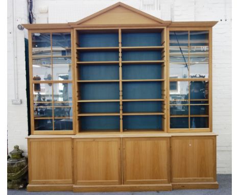 A large 18th century style light oak breakfront bookcase, with architectural cornice over open shelves flanked by glazed cupb