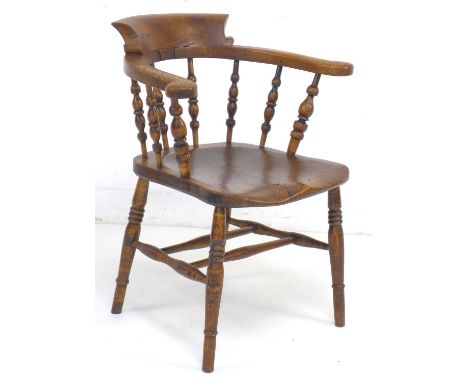 A 19th century burr oak and elm smoker's bow armchair, with shaped arms supported on turned spindles, saddle seat, stamped to