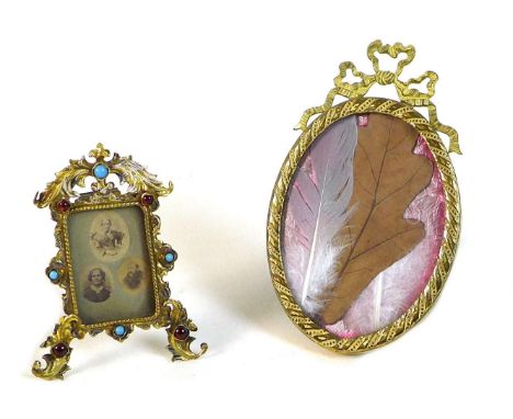 Two 19th century gilt brass easel photograph frames, one rectangular with foliate clasped frame, set with cabochon red glass 