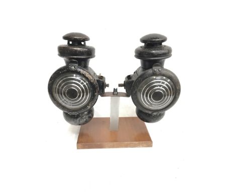 Two Ford Model T veteran side lamps with bulls eye lens. Lens diameter 8.5cm, height 24cm. Mounted on display plinth. 