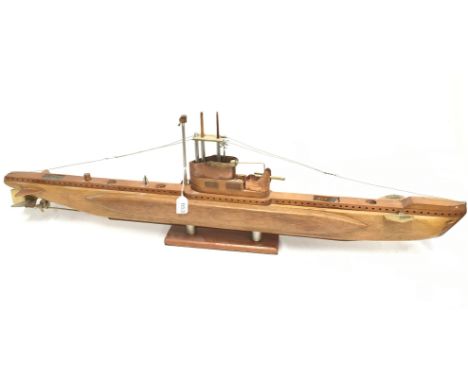 A well-built submarine model, of wooden construction with metal fittings, mounted on display plinth. Length 99cm. 