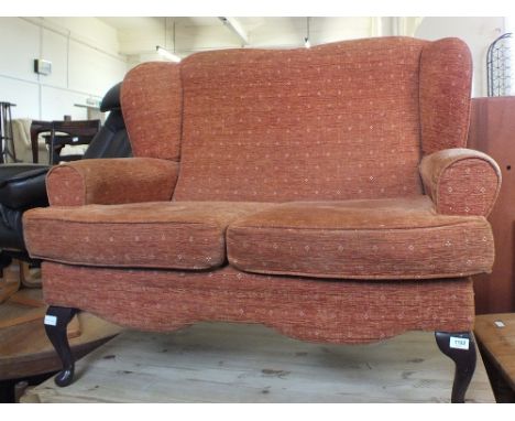 A two seater wingback sofa with terracotta upholstery and cabriole legs