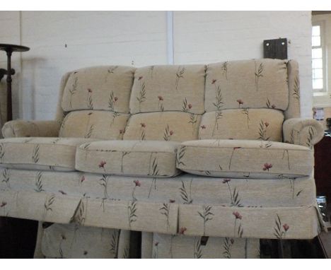 A modern three seater sofa in beige upholstery with poppy design and two matching armchairs
