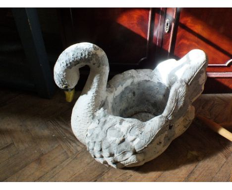 A large weathered concrete garden planter in the form of a swan