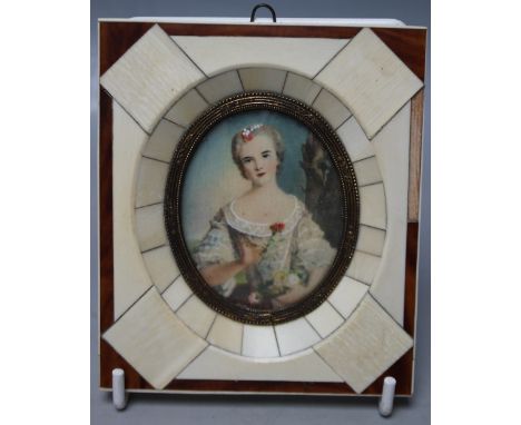 A 20TH CENTURY OVAL PORTRAIT MINIATURE OF IVORINE, a portrait study of a young woman holding a flower, unsigned, framed in a 