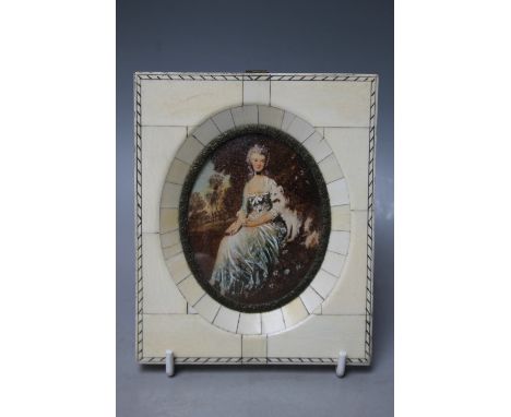 A 20TH CENTURY OVAL PORTRAIT MINIATURE ON IVORINE depicting a seated young woman with dog, trees in background, unsigned, fra