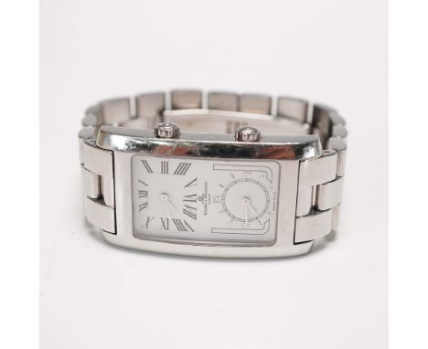 Swiss-made Baume &amp; Mercier Hampton dual time wrist watch crafted in stainless steel. This rectangular-shaped watch featur