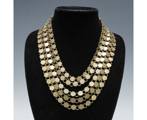 Bold gold tone necklace featuring layered strands of flat round disc links that create a striking draped silhouette. Secured 