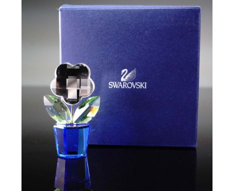 This Swarovski crystal flower figurine features a stylized clear crystal blossom with a faceted surface, vibrant green leaves