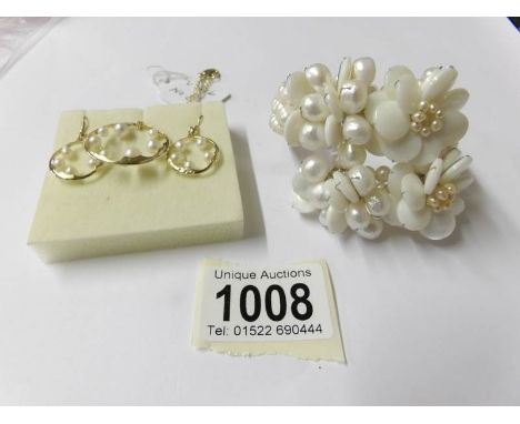A Butler and Wilson cultured pearl and mother of pearl bangle together with cultured pearl earrings and matching pendant.