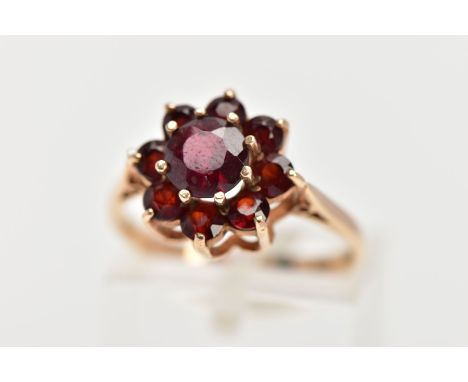 A GARNET CLUSTER RING, the central circular garnet within a tiered circular garnet surround, all within claw settings, stampe
