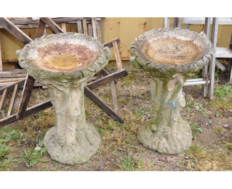 A PAIR OF COMPOSITE ONE PIECE BIRD BATHS in the form of a tree trunk with foliate bowl and birds at opposing sides height 70c