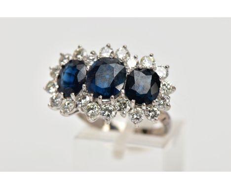 A LARGE SAPPHIRE AND DIAMOND TRIPLE CLUSTER RING. Largest blue sapphire measuring approximately 8.3mm x 7.0mm, the two outer 