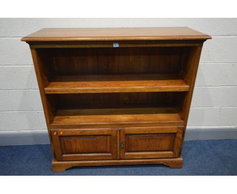 A REPRODUCTION OAK OPEN BOOKCASE, with fielded panels to the sides, single adjustable shelf, above double cupboard doors, wid