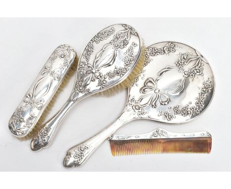 A FOUR PIECE SILVER VANITY SET, to include a hairbrush, clothes brush, comb and a handheld mirror, each with an embossed flor