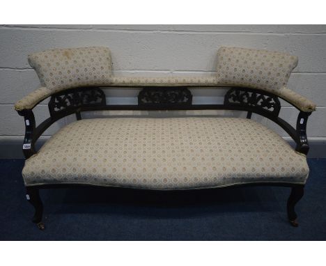 AN EDWARDIAN EBONISED SOFA, with a carved fretwork back, width 139cm