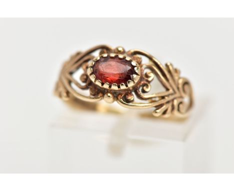 A 9CT GEM RING, the central oval red gem, assessed as paste, to the scrolling openwork design to the half band, 9ct hallmark 