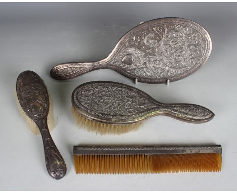 An Indian silver three-piece dressing table set, comprising hand mirror, hairbrush and comb, each decorated in relief with fo