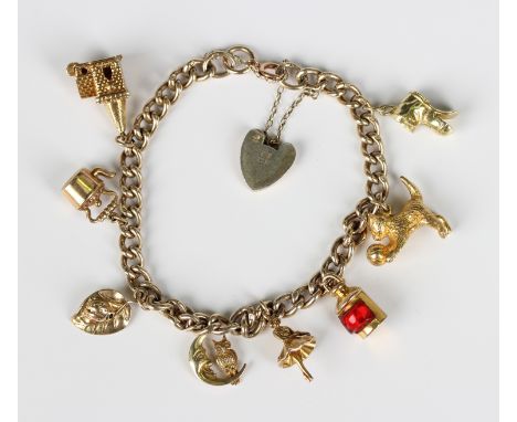 A silver gilt curblink charm bracelet on a silver gilt heart shaped padlock clasp, fitted with eight 9ct gold charms, includi