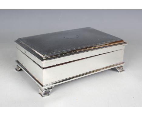 A George V silver rectangular trinket box with engine turned hinged lid, on bracket feet, with fitted silk and velvet interio