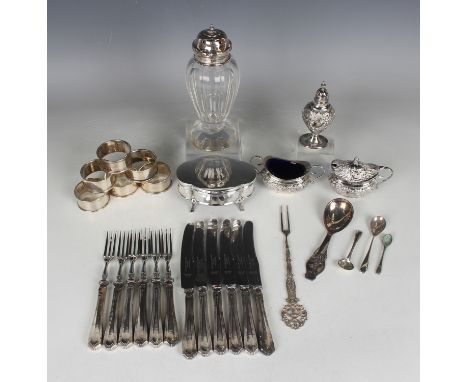 An Edwardian silver three-piece condiment set of oval shape, embossed with foliate scrollwork and trellis around a vacant car
