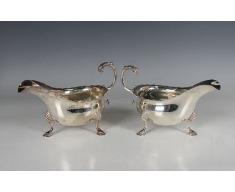 A pair of Edwardian silver sauceboats, each with a foliate capped flying scroll handle, on scroll legs terminating in hoof fe