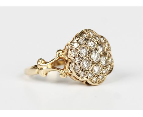 A gold and diamond cluster ring in a flowerhead shaped design, mounted with circular cut diamonds between split scrolled shou