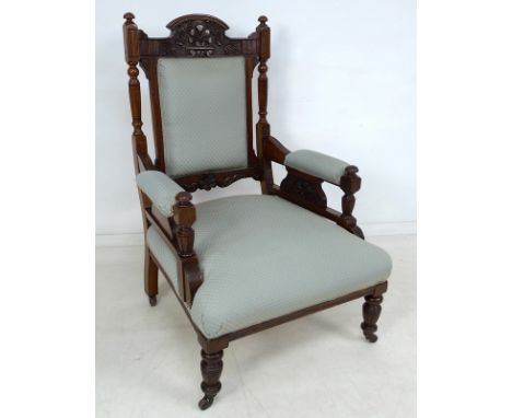 A Victorian walnut framed open armchair, with carved floral crest and turned spindles to the back, padded arms supported on c