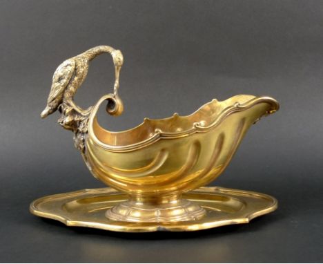 An Elizabeth II silver sauce boat with spoon and stand, the handle of the heavily gilded boat finely cast as a crane perched 