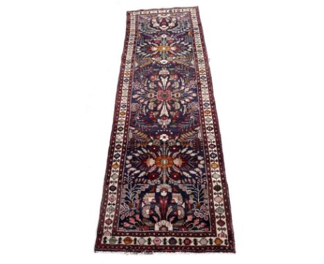 A Hamadan runner with dark blue ground, large scale floral medallions linked across the length, narrow cream border with simp