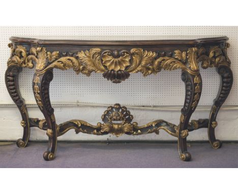 CONSOLE TABLE, by Theodore Alexander, of serpentine form, the mahogany top on an elaborately carved base with gilt detail and