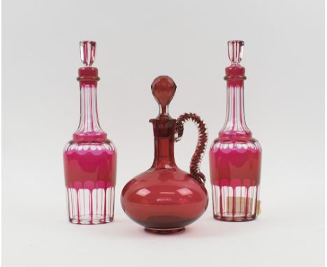 DECANTERS, a pair, red flashed and slice cut in the Bohemian manner, 31cm H; plus a ruby glass carafe with twist loop handle,