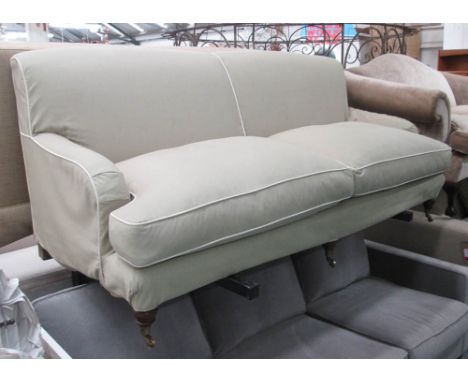 SOFA, Howard style with a loose green cover with cream piping on short turned front supports with cappings and castors, 189cm