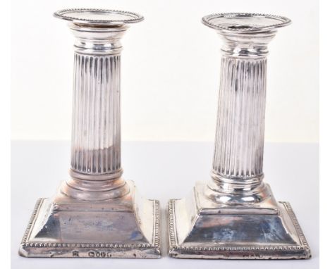 A pair of Victorian squat Corinthian column candlesticks, by William Hutton, London 1881, bead border decoration, raised on s