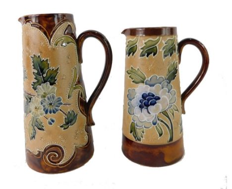 Two Royal Doulton Lambeth stoneware jugs, each with a brown border, on a glazed light brown body with blue flowers, 20cm high