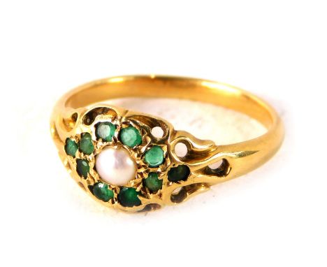 An emerald and cultured pearl dress ring, formed as a floral cluster with pierced and scroll outer border, on a yellow metal 