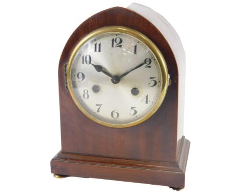 An early 20thC mahogany and chequer banded mantel clock, with an arched top and a silvered dial, 26cm high. 