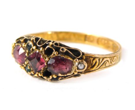 A 15ct gold ruby gypsy ring, set with two oval rubies and a square cut central ruby, with tiny emeralds and seed pearls with 