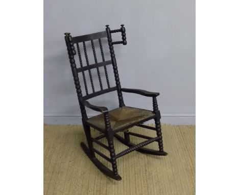 A Child's ebonised ash and beech rocking chair in the manner of Ernest Gimson for Robert Weir Schulz with bobbin turned uprig