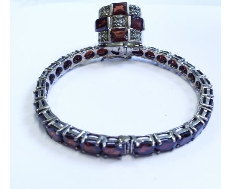 A silver and garnet bangle, and a ring (2)

We will post this item worldwide at cost. No packing charge. 