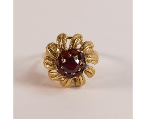 Yellow metal dress ring, electronically tested as 18ct gold, palm tree like setting with dark red/brown stones, size L, 5.6g.