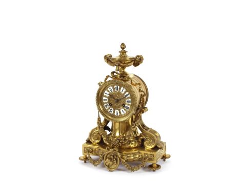 A 19th Century French brass mantel clock, surmounted by an urn with ram's head mask and pineapple finials, the whole decorate