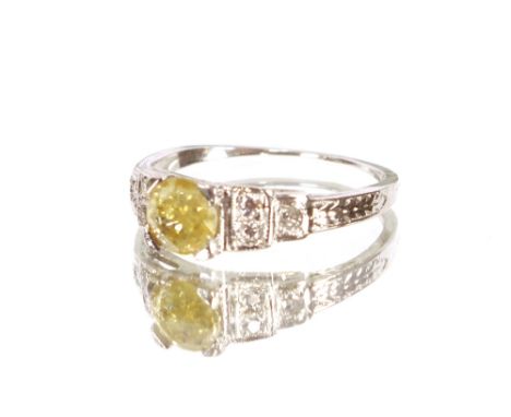 An antique fancy yellow diamond and 18 carat white gold ring, the central stone approx. 1/2 carat, set with six small diamond