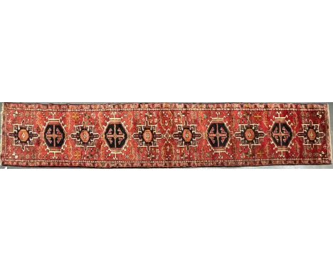 An early 20th century North West Persian Islamic Heriz floor carpet runner rug. The rug on red ground with series of repeatin