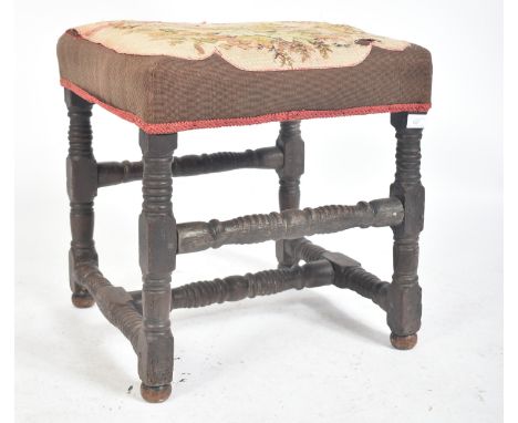 A 18th century English oak and tapestry upholstered stool. The stool with tapestry overstuffed seat raised on block and ring 