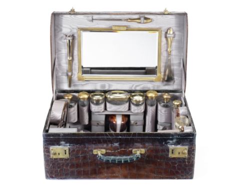 A crocodile skin case and silver-gilt travelling setCharles Henry Dumenil, London 1911, 1913, 1914The case with fitted interi